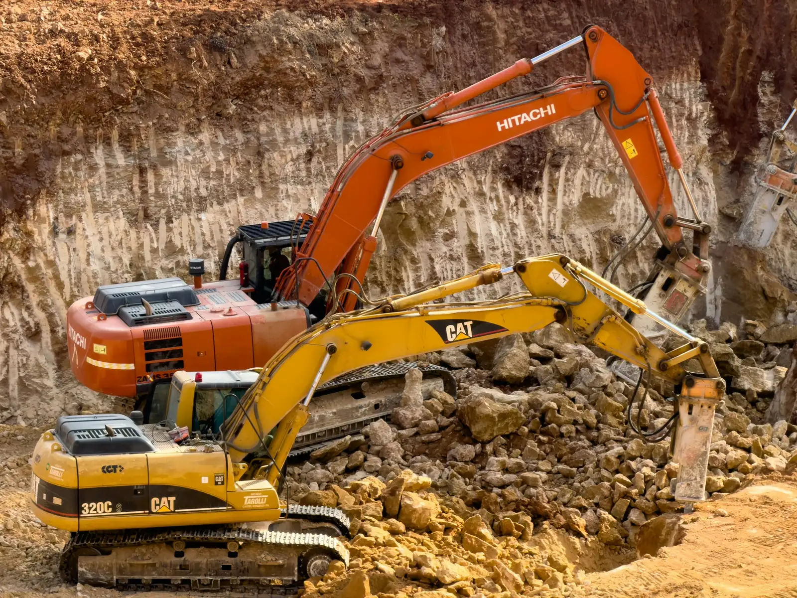 Two excavators breaking and loading rock at the foot of a cutting